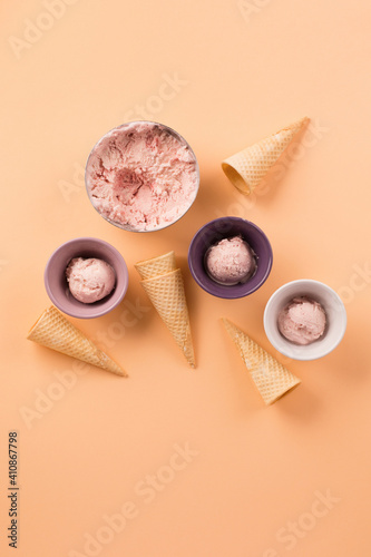 Homemade yogurt strawberry ice cream, sweet waffle cones on pastel beige background.