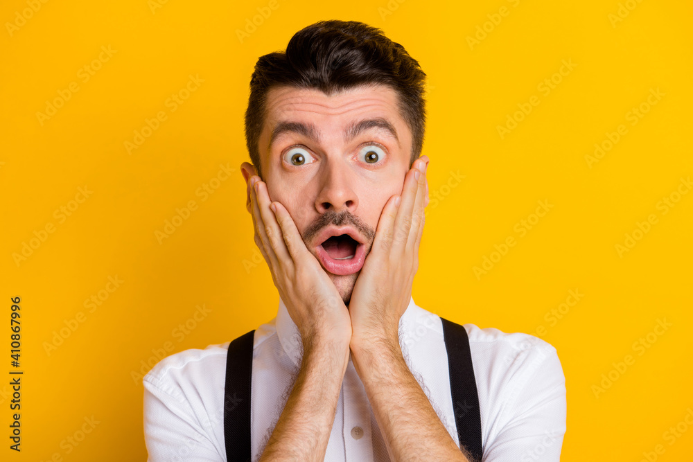 Portrait of funny attractive worried guy wearing white shirt unexpected news reaction isolated over bright yellow color background