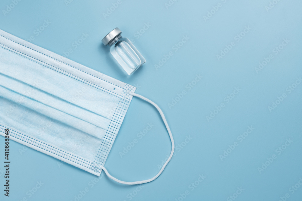 Blue face masks or medical protective mask and vaccine bottle on blue background with copy space. Coronavirus or covid-19 protective mask. Hygiene or healthy concept.