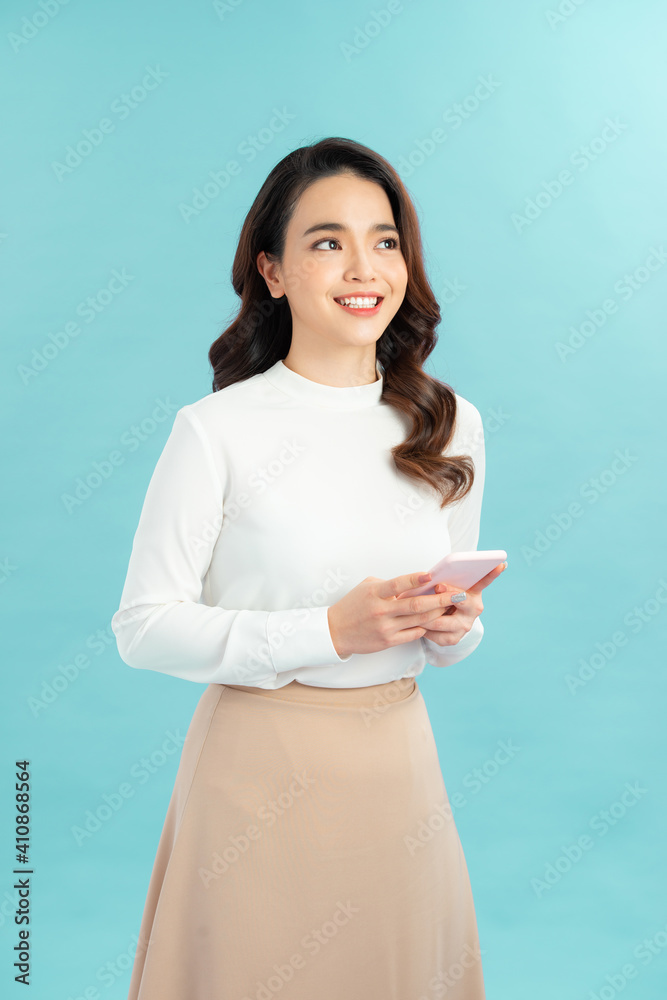 Portrait of a happy asian businesswoman using mobile phone isolated over blue background Portrait of a happy asian businesswoman using mobile phone isolated over blue background
