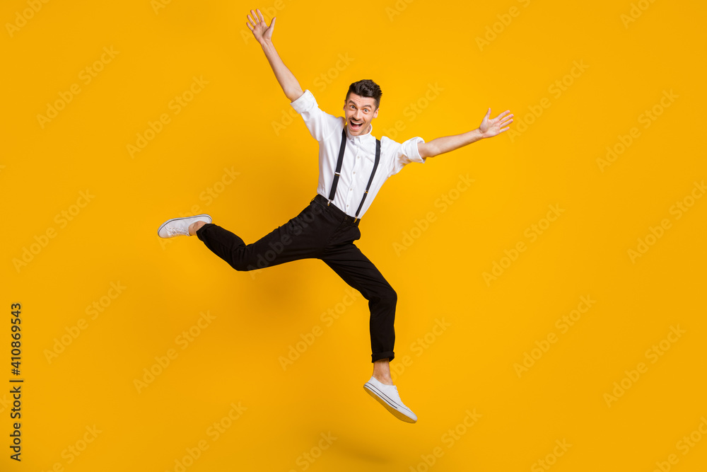 Full length body size photo of jumping man dancing at party cheerful wearing suspenders isolated on vivid yellow color background
