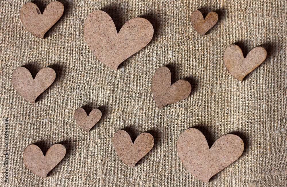 Decorative wooden hearts on burlap canvas background, love and valentine's day concept