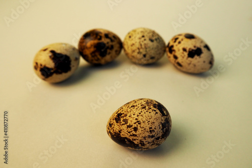 five raw quail eggs lie side by side on a light beige background . healthy eating