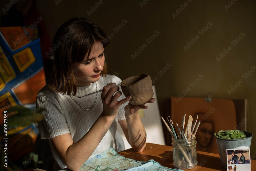 young artist moulding raw clay in art studio. Girl molds from clay sculpture in the artist's studio. Business woman at her pottery store