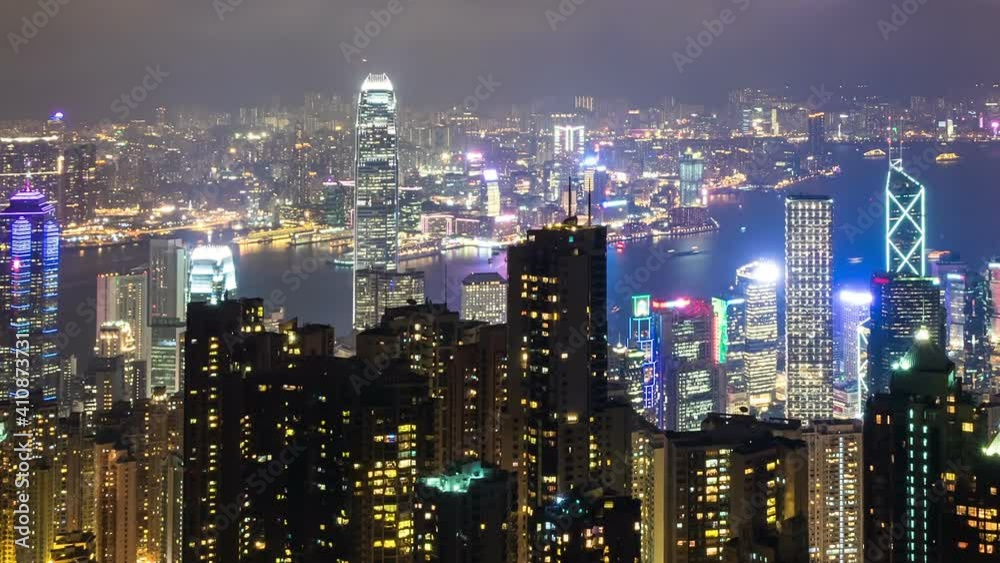 Hong Kong city skyline at night with Victoria Harbor and skyscrapers illuminated by lights over water viewed from mountain top. Hong Kong city skyline at night with Victoria Harbor and skyscrapers illuminated by lights over water viewed from mountain top.