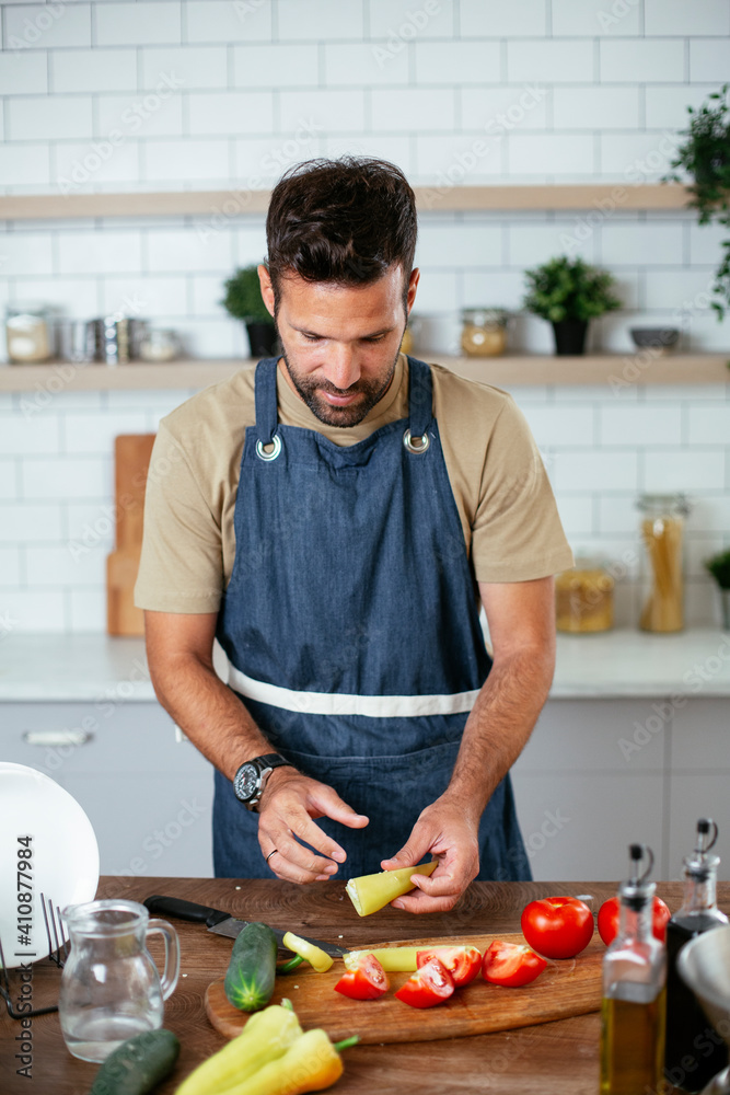 Portrait of handsome man in kitchen. Young man preparing salad Portrait of handsome man in kitchen. Young man preparing salad