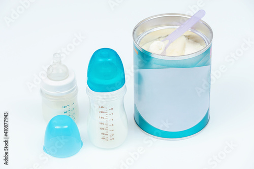 Baby powder milk formula in a can next to baby bottles