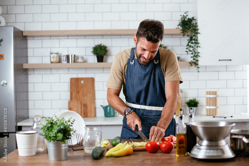 Portrait of handsome man in kitchen. Young man preparing salad Portrait of handsome man in kitchen. Young man preparing salad