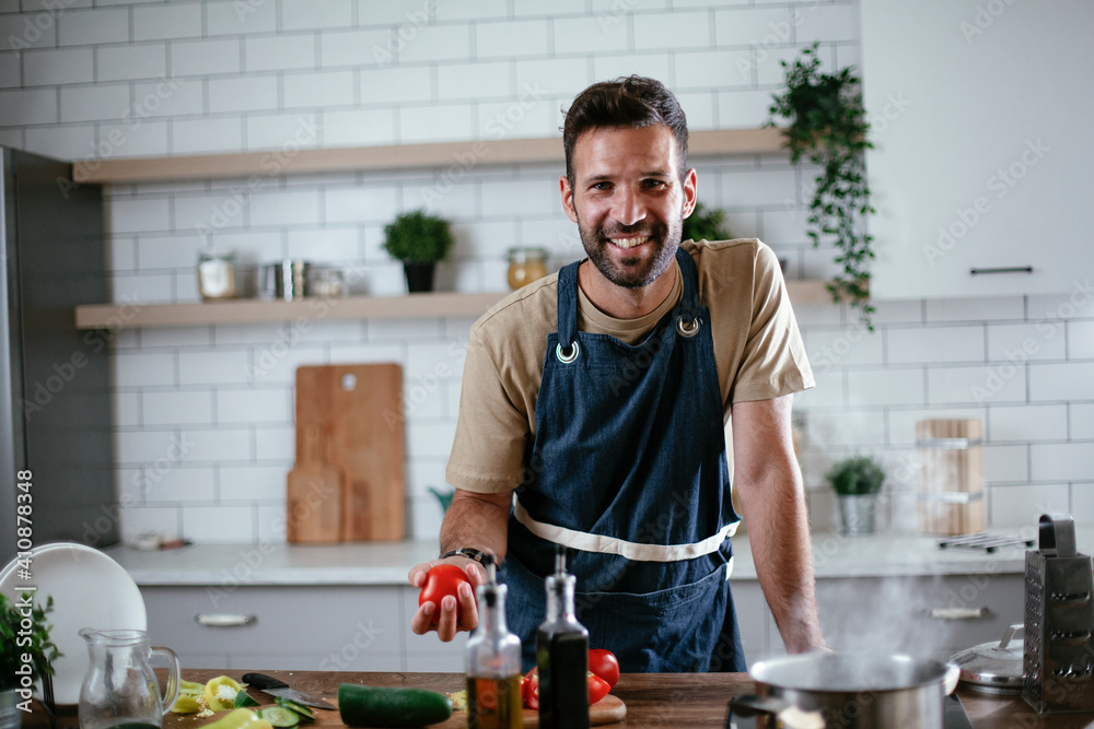 Happy man in kitchen. Young man preparing delicious food