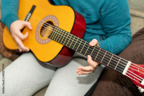 detail of a young man's hands on the frets of the Spanish guitar practicing a lesson.