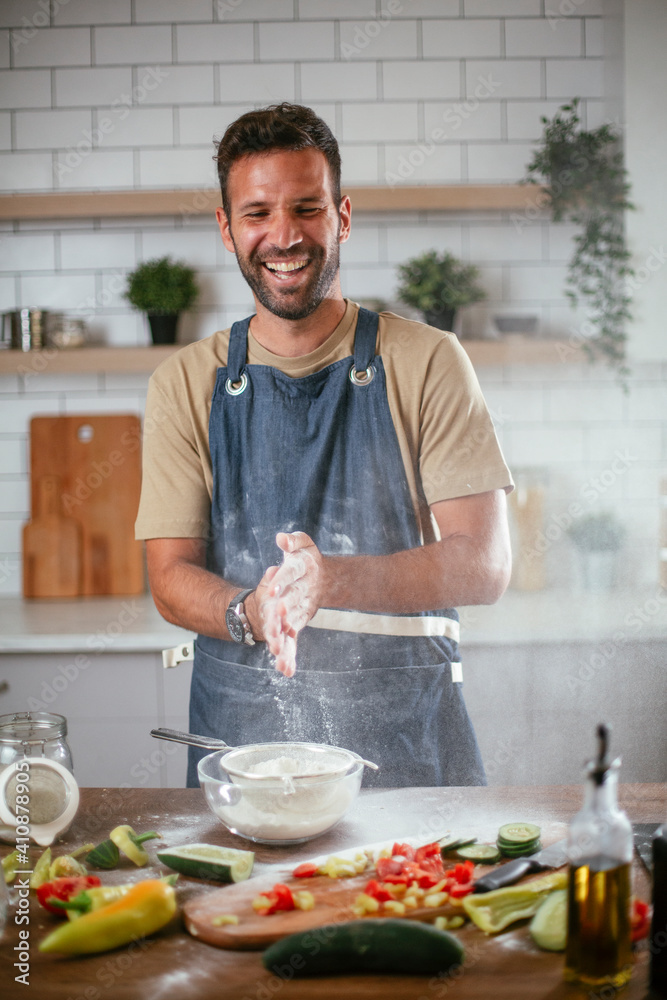 Happy man baking in the kitchen. Man making fresh pasta Happy man baking in the kitchen. Man making fresh pasta
