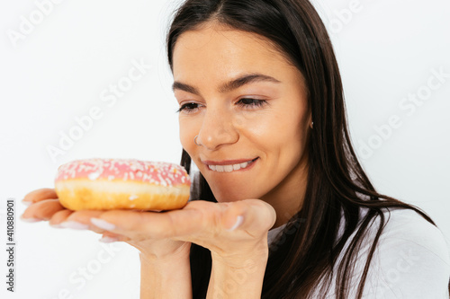 Close-up portrait of happy smiling young woman looking at delicious donut