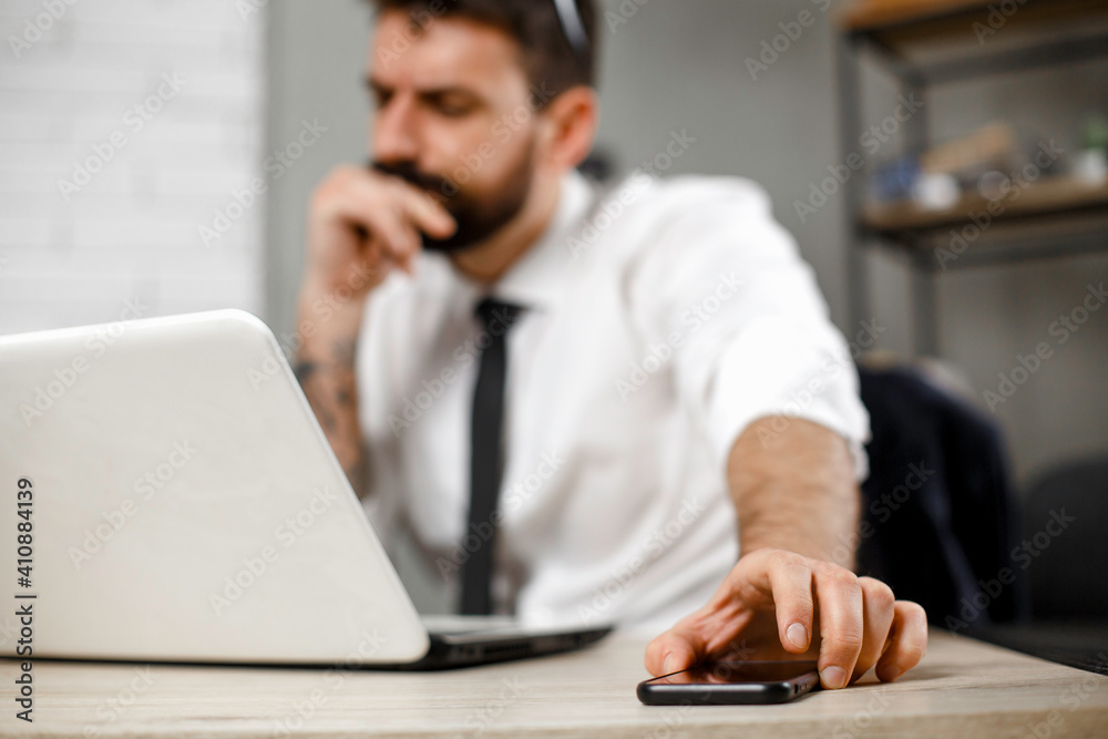 Young businessman working on laptop at office. Businessman sitting at office desk working on new project Young businessman working on laptop at office. Businessman sitting at office desk working on new project