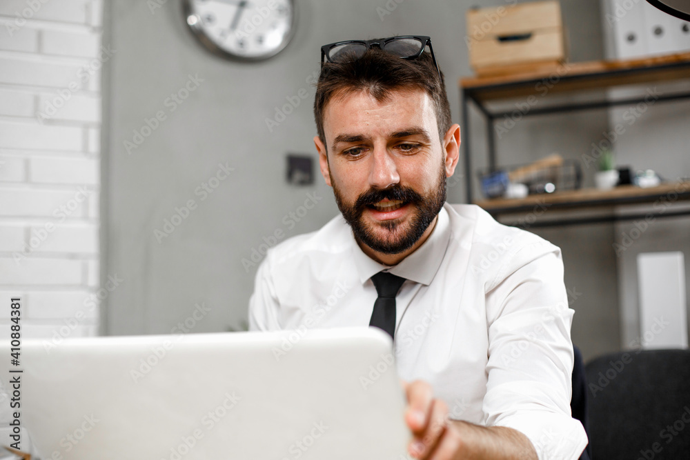 Young businessman working on laptop at office. Businessman sitting at office desk working on new project Young businessman working on laptop at office. Businessman sitting at office desk working on new project