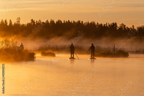 Amazing view of two asian girls doing SUP stand up paddle boarding at sunrise in lake. Early summer morning activity