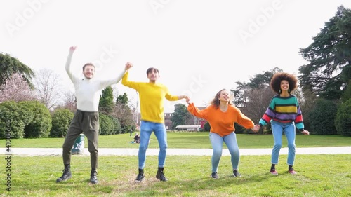 Slow motion group of for multiethnic people friends jumping in a parkl celebrating good times feeling free having fun photo
