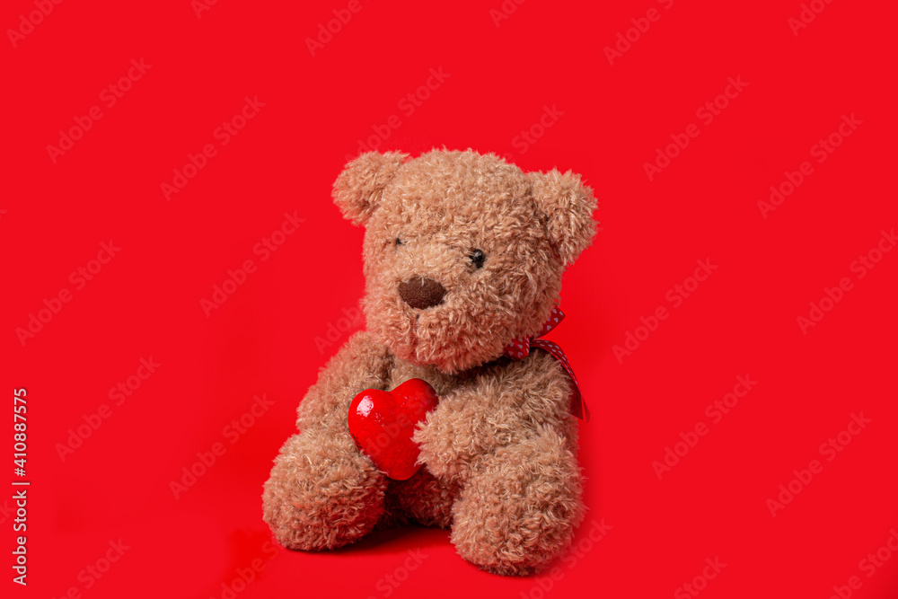Teddy bear holding a heart on a red background Teddy bear holding a heart on a red background