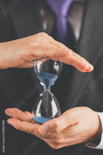 Business man holding hourglass in hand