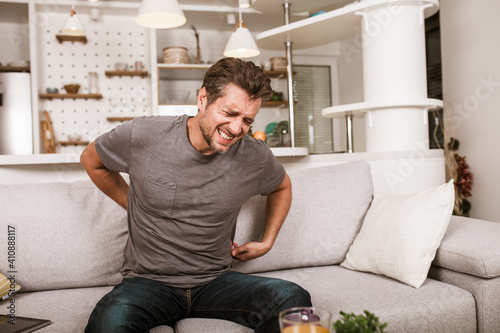 Unhappy man suffering from backache at home