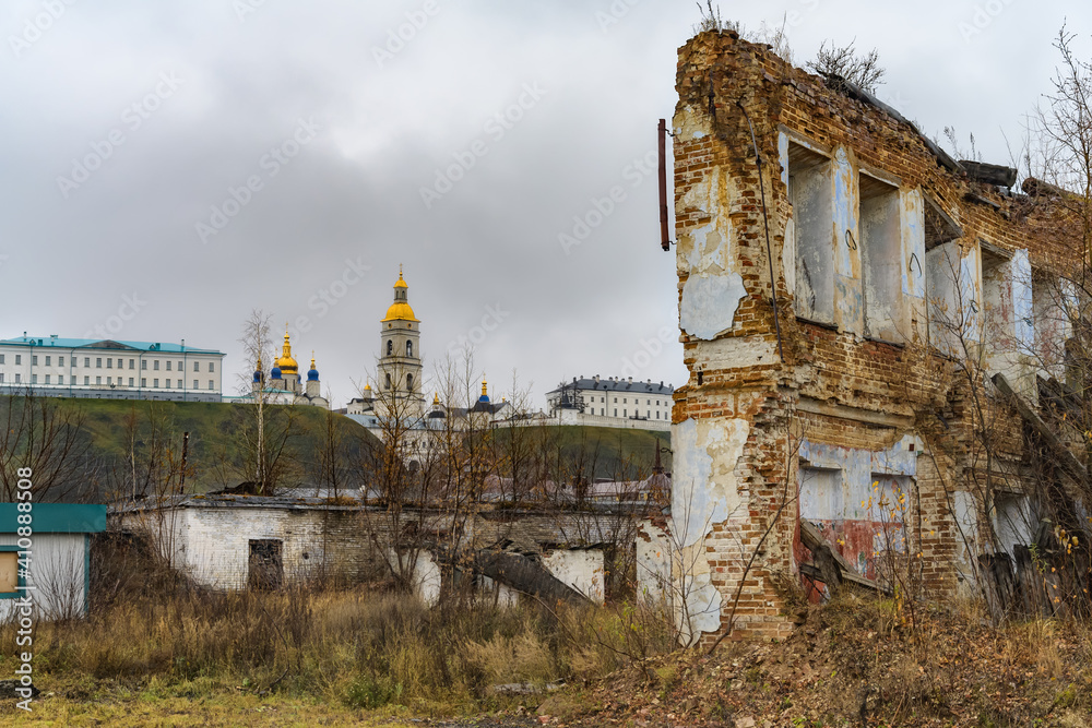 The old part of Tobolsk (Russia), not yet restored, with dilapidated houses-monuments of architecture in autumn. The pearl of the city is visible in the distance - its Kremlin with golden domes The old part of Tobolsk (Russia), not yet restored, with dilapidated houses-monuments of architecture in autumn. The pearl of the city is visible in the distance - its Kremlin with golden domes