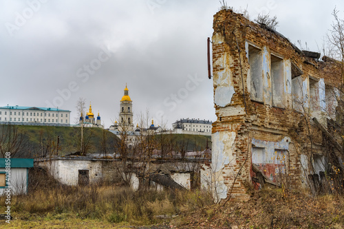 The old part of Tobolsk (Russia), not yet restored, with dilapidated houses-monuments of architecture in autumn. The pearl of the city is visible in the distance - its Kremlin with golden domes 