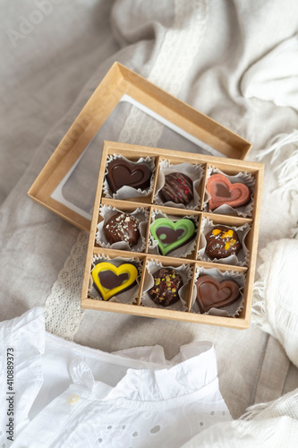 A box of chocolate mix of chocolates stands on the table in the morning light. Beautiful sweet gift for the wedding, for the birthday, for the holiday