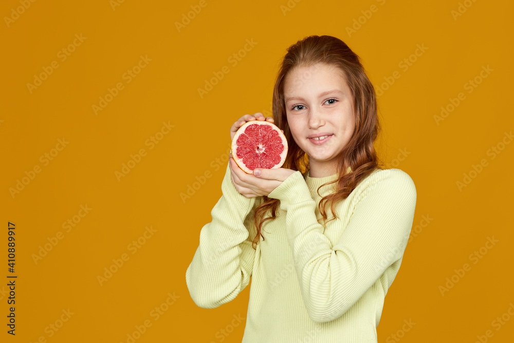 adorable redhead little child girl holding fresh juicy grapefruit isolated on yellow background adorable redhead little child girl holding fresh juicy grapefruit isolated on yellow background
