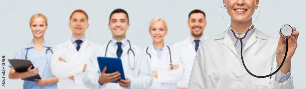 medicine, cardiology and healthcare concept - close up of happy smiling female doctor in white coat with stethoscope over medical team on grey background medicine, cardiology and healthcare concept - close up of happy smiling female doctor in white coat with stethoscope over medical team on grey background