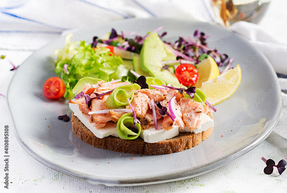 Sandwich with baked salmon. Tapas. Sandwich with salmon, feta cheese, avocado and microgreens.