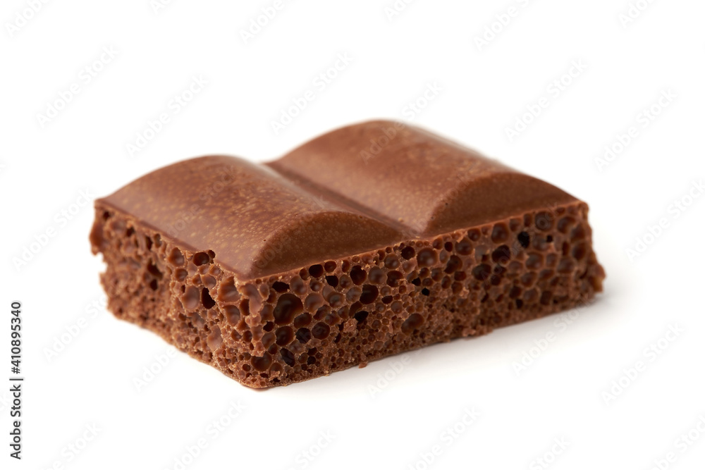 Close-up of a piece of porous milk chocolate isolated on white background
