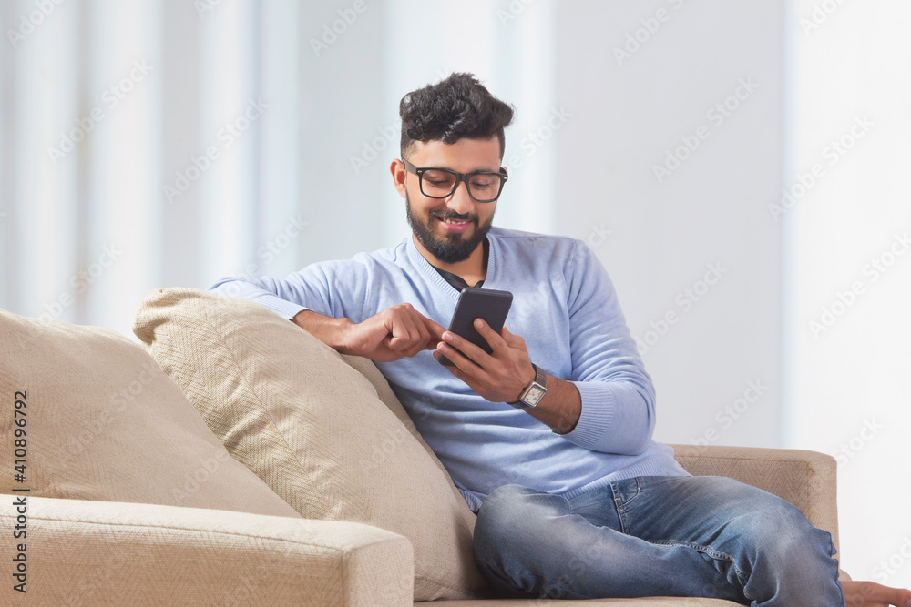 Young man sitting on the couch and using his mobile. Young man sitting on the couch and using his mobile.