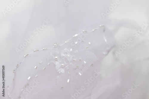 Delicate white tulle background. Blurred wedding veil with beads closeup. Selective focus