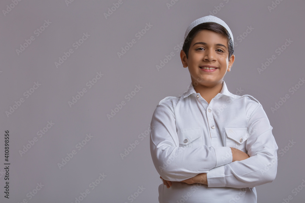 young muslim boy wearing cap folding hands and smiling	
