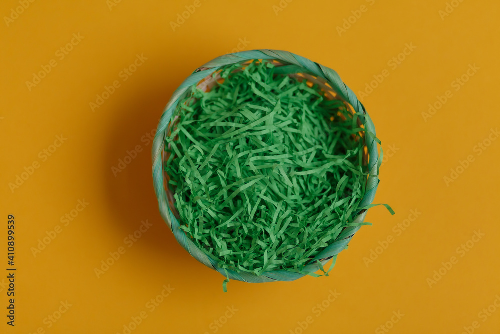 Green basket for easter eggs on a yellow background Green basket for easter eggs on a yellow background