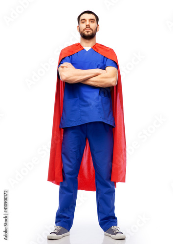 healthcare, profession and medicine concept - doctor or male nurse in blue uniform and red superhero cape over white background