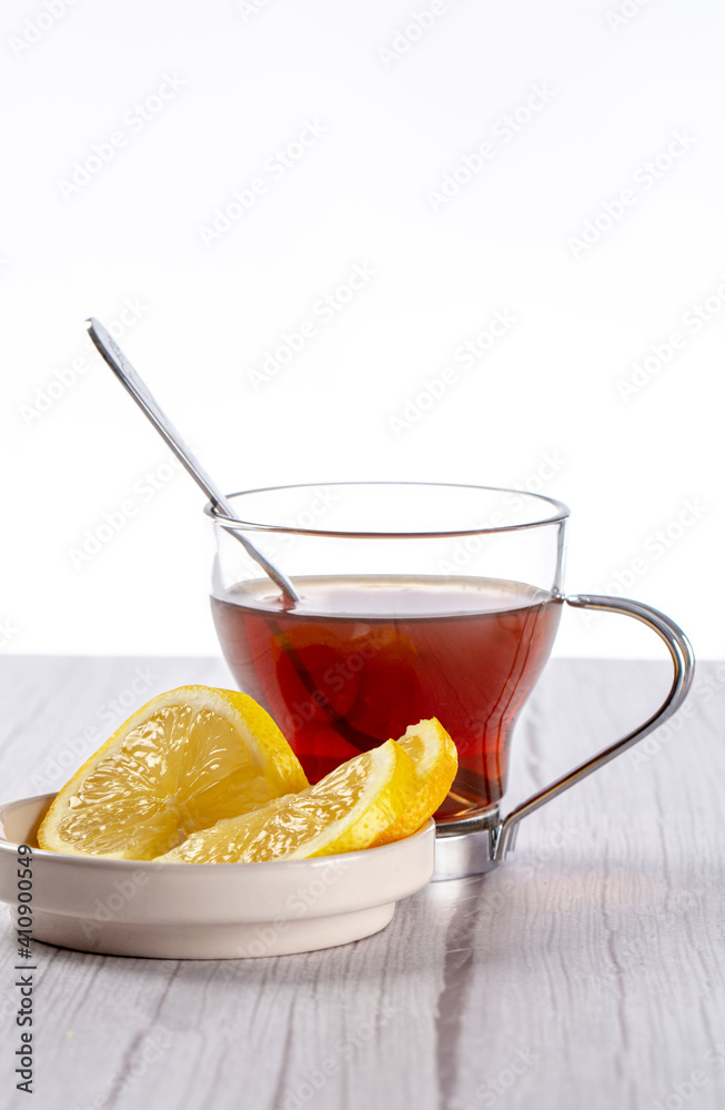 Cup of tea with teaspoon accompanied by a saucer with lemon slices Cup of tea with teaspoon accompanied by a saucer with lemon slices