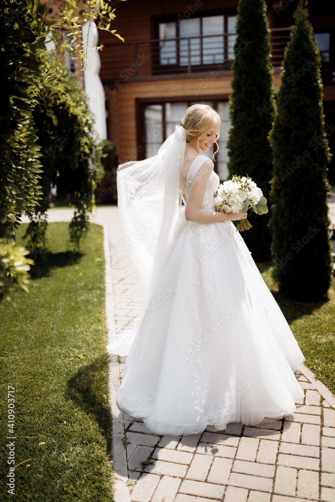 Fototapeta premium bride in a dress standing in a green garden and holding a wedding bouquet of flowers and greenery