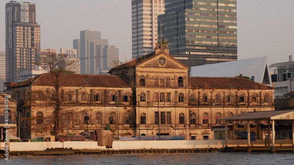Fototapeta premium January 2 2021 - Bangkok, Thailand : Beautiful Old Customs House at Chao praya River and high modern building as background
