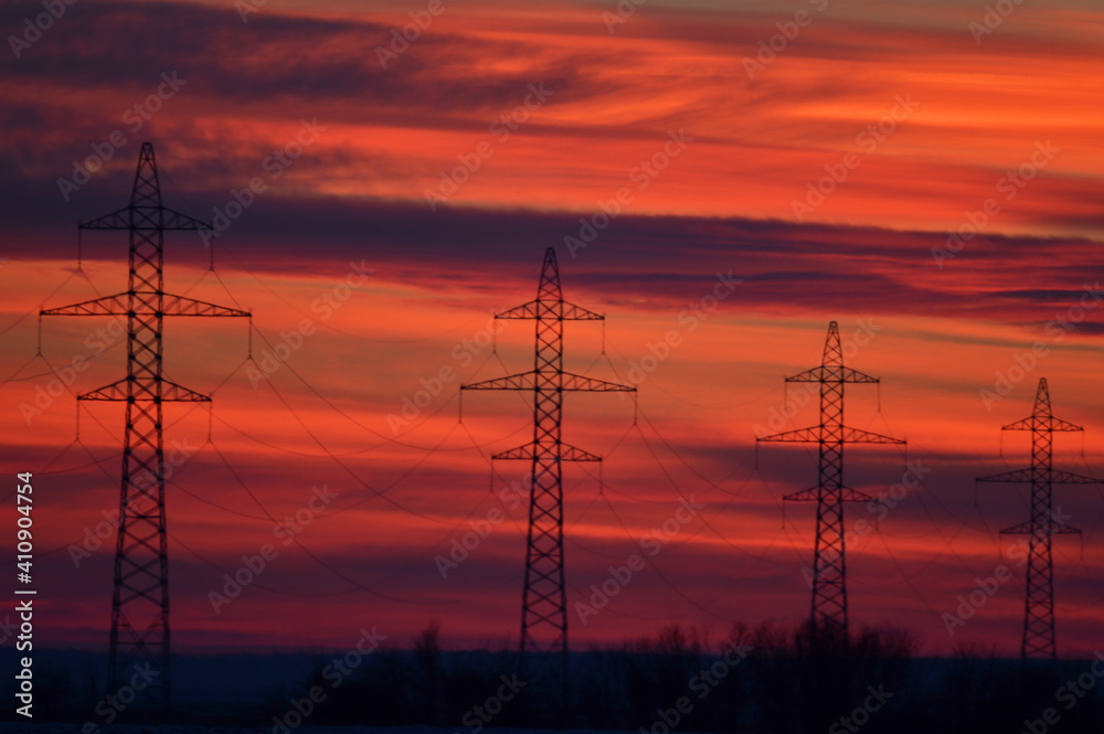 Fototapeta premium High voltage poles photographed at a beautiful sunset. Red background.