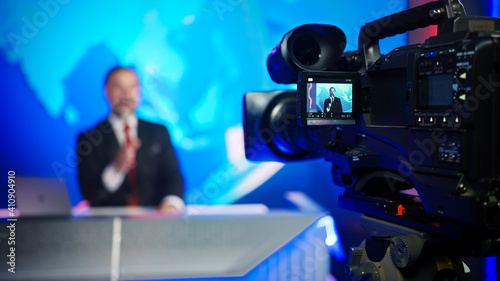 Canvas Print Professional TV Camera Standing in Live News Studio with Anchor seen in Small Display