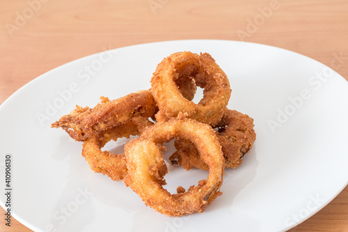 Fried breaded onion rings on platter as appetizer.