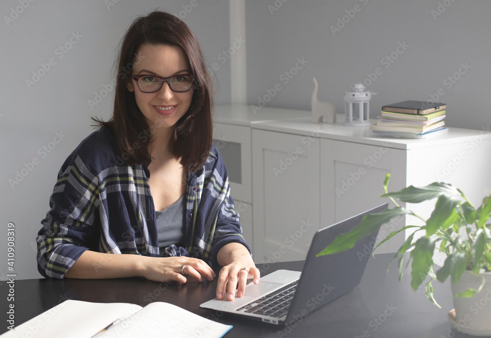 Young smiling woman freelancer working on laptop from home office. Self-employment and freelance concept, comfortable work from home Young smiling woman freelancer working on laptop from home office. Self-employment and freelance concept, comfortable work from home
