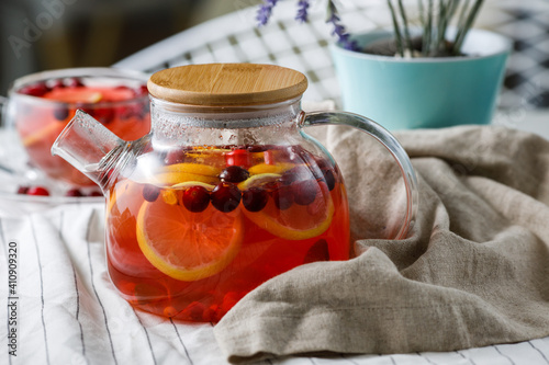 teapot of red berry tea with lemon on a light background