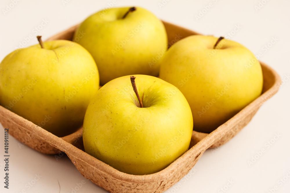 Close up of fresh yellow apples on biodegradable pulp paper food tray isolated on white. Recyclable packagingбsustainable consumption concept. Close up of fresh yellow apples on biodegradable pulp paper food tray isolated on white. Recyclable packagingбsustainable consumption concept.