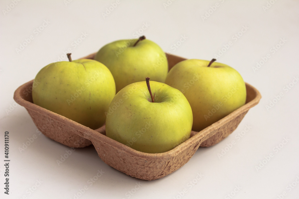 Fresh green apples on biodegradable pulp paper food tray isolated on white. Recyclable packaging concept. Side view, copy space Fresh green apples on biodegradable pulp paper food tray isolated on white. Recyclable packaging concept. Side view, copy space