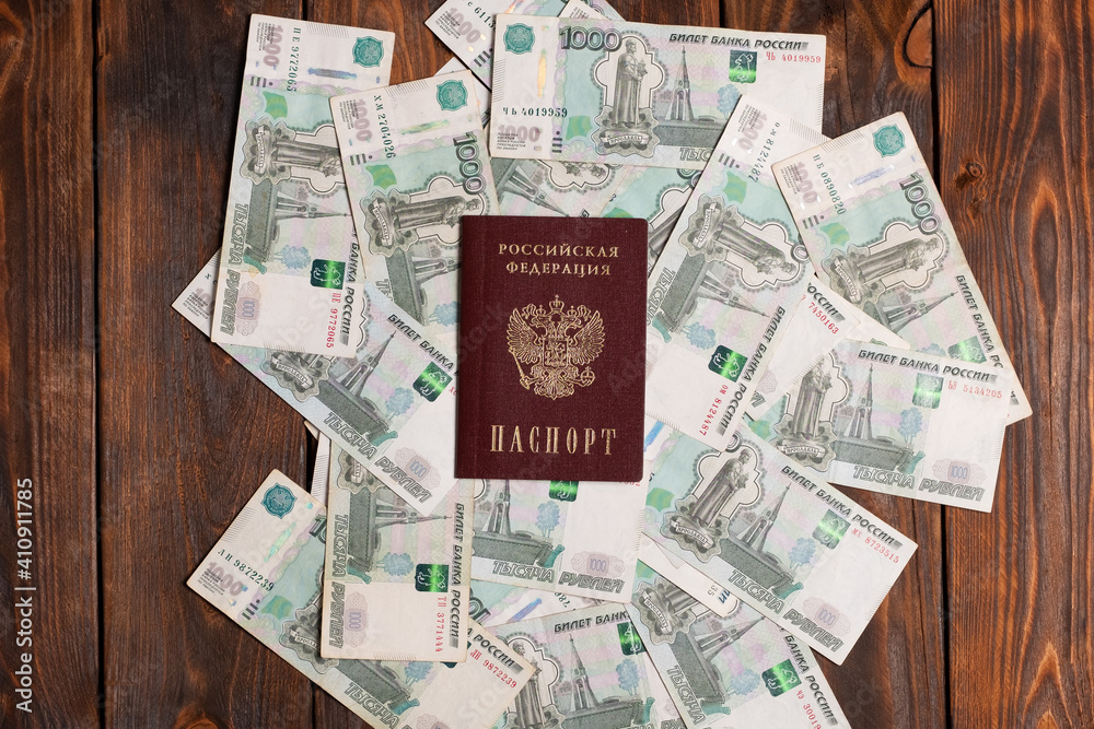 Russian passport with money for shopping abroad, travel and entertainment. Money is lying on wooden background.