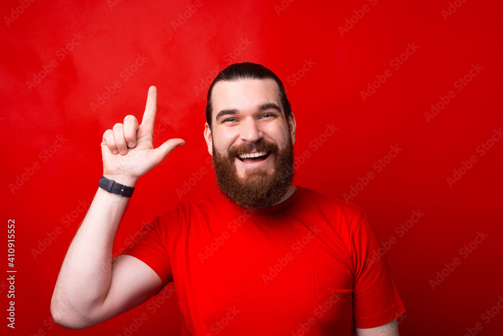 Photo of amazed bearded man pointing up over red background. Photo of amazed bearded man pointing up over red background.