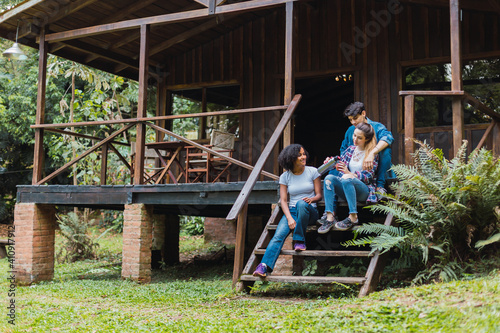 Multiracial friends drinking mate in a cabin.