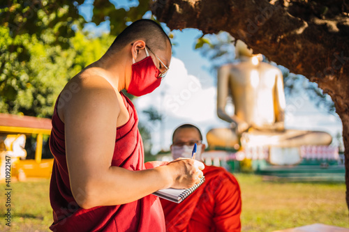 Buddhist monks in their free time at the temple, writing and enjoying the outdoors.