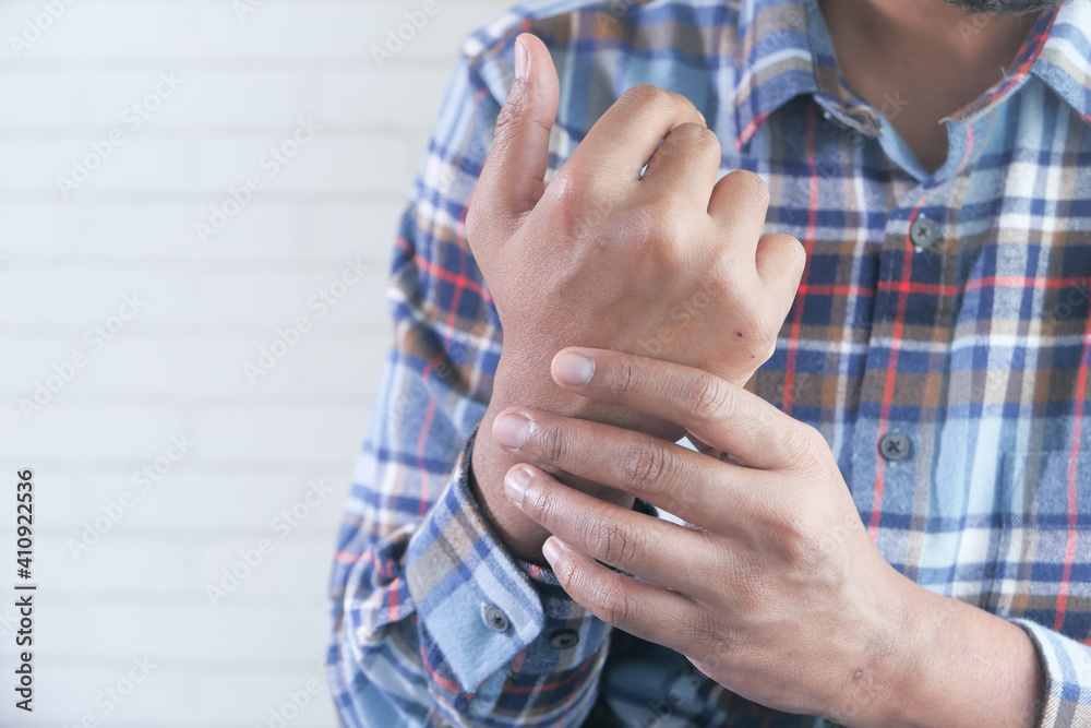 man holding his wrist and suffering pain in hand with copy space 